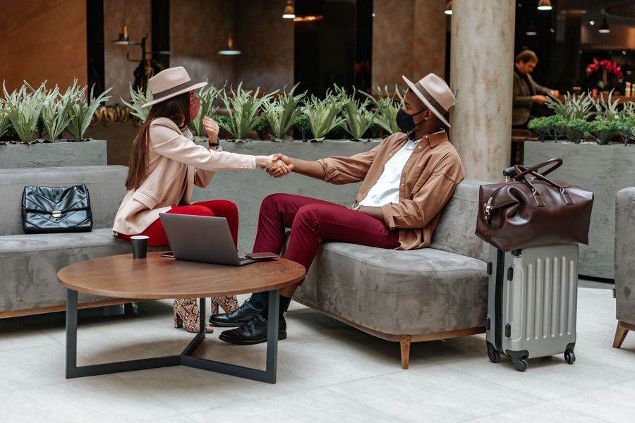 Travellers greeting each other in an airport lounge with luggage
